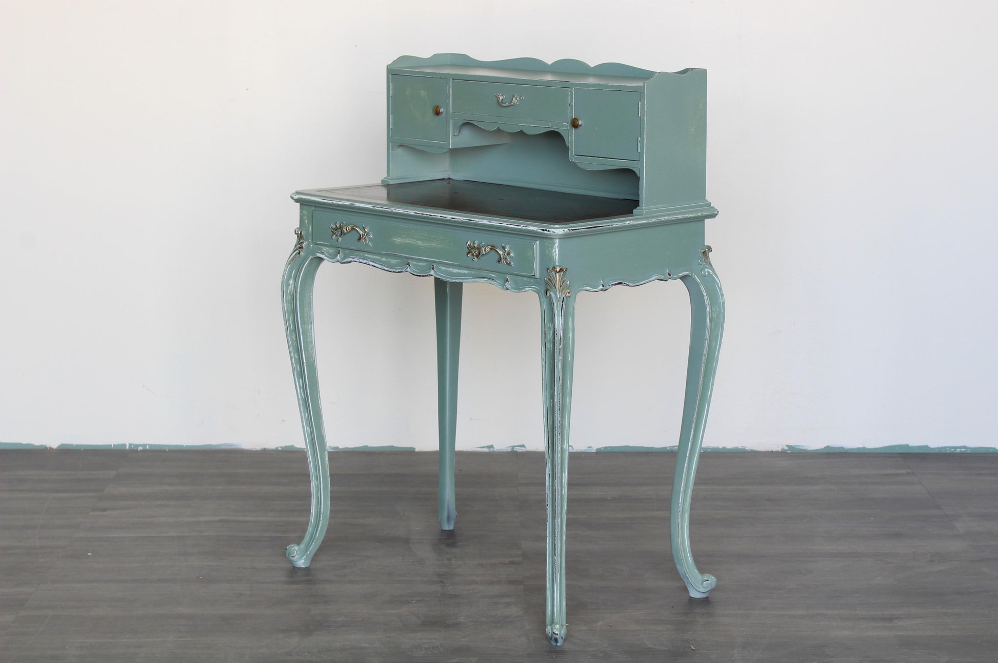 Vintage French style secretary desk.  This desk is solid built with leather top.  This desk is professionally refinished in light green, beautifully distressed in a clear satin top coat with gold painted accents.  Dimensions: 28"Width x 17"Depth x 39"Height x 29"Top Height. 