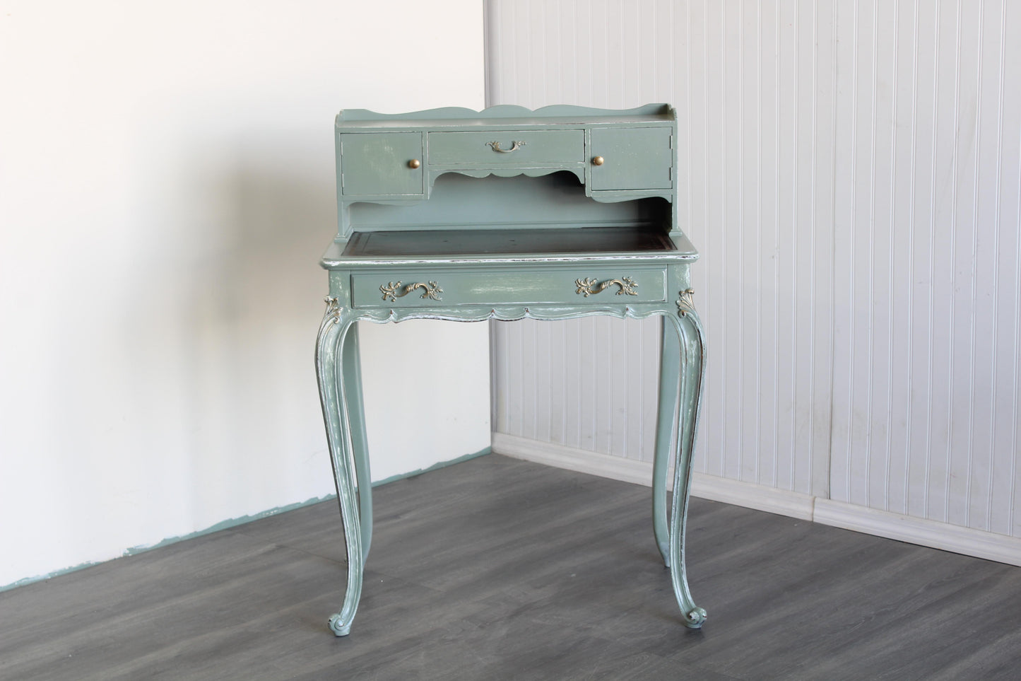 Vintage French style secretary desk.  This desk is solid built with leather top.  This desk is professionally refinished in light green, beautifully distressed in a clear satin top coat with gold painted accents.  Dimensions: 28"Width x 17"Depth x 39"Height x 29"Top Height. 