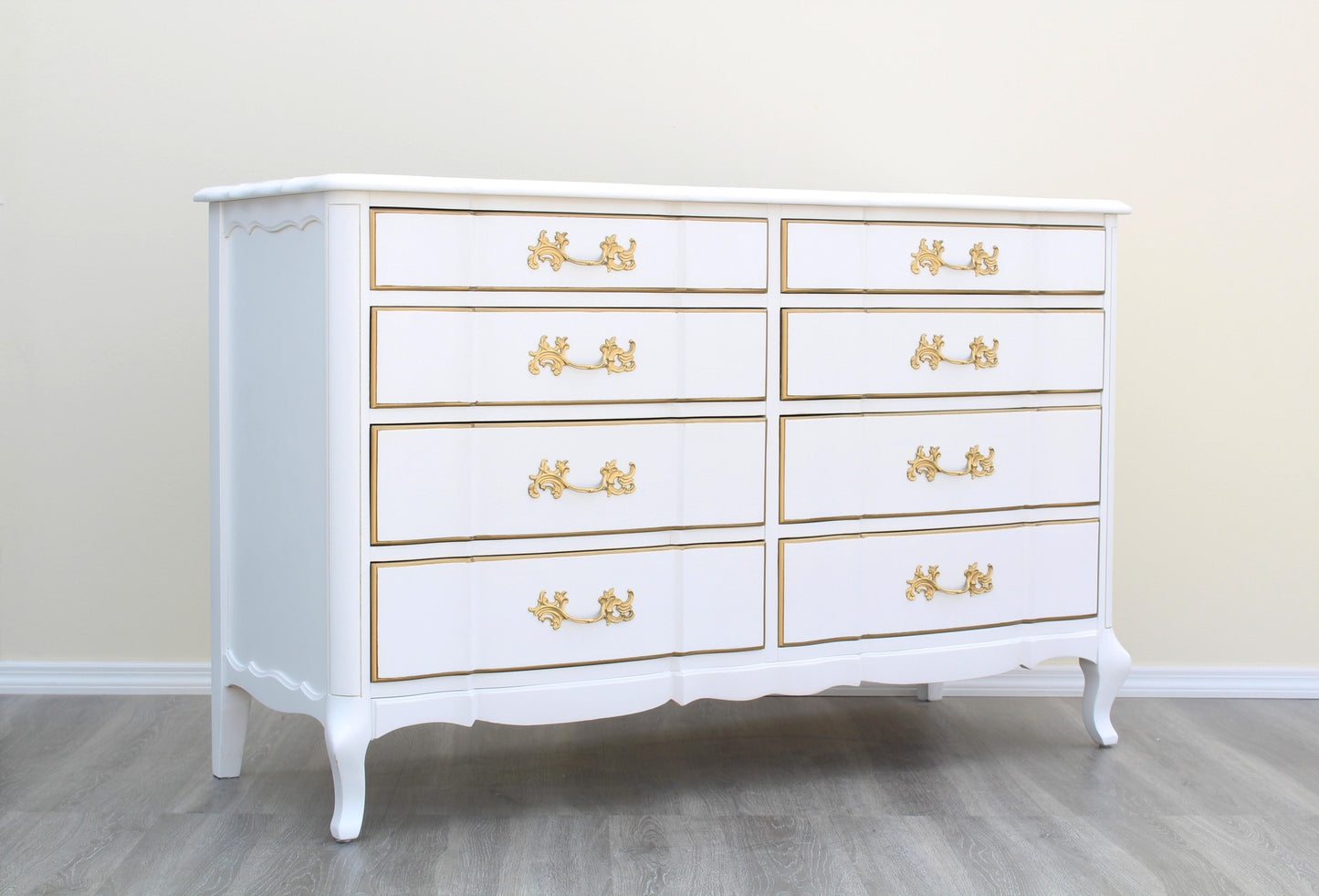 1970's French Provincial Dresser of Eight Drawers by Permacraft.  This dresser is solid built with dovetail joints and metal hardware, is newly refinished in white and gold with a satin topcoat.  Dimensions: 54"Width x 20"Depth x 34"Height. 