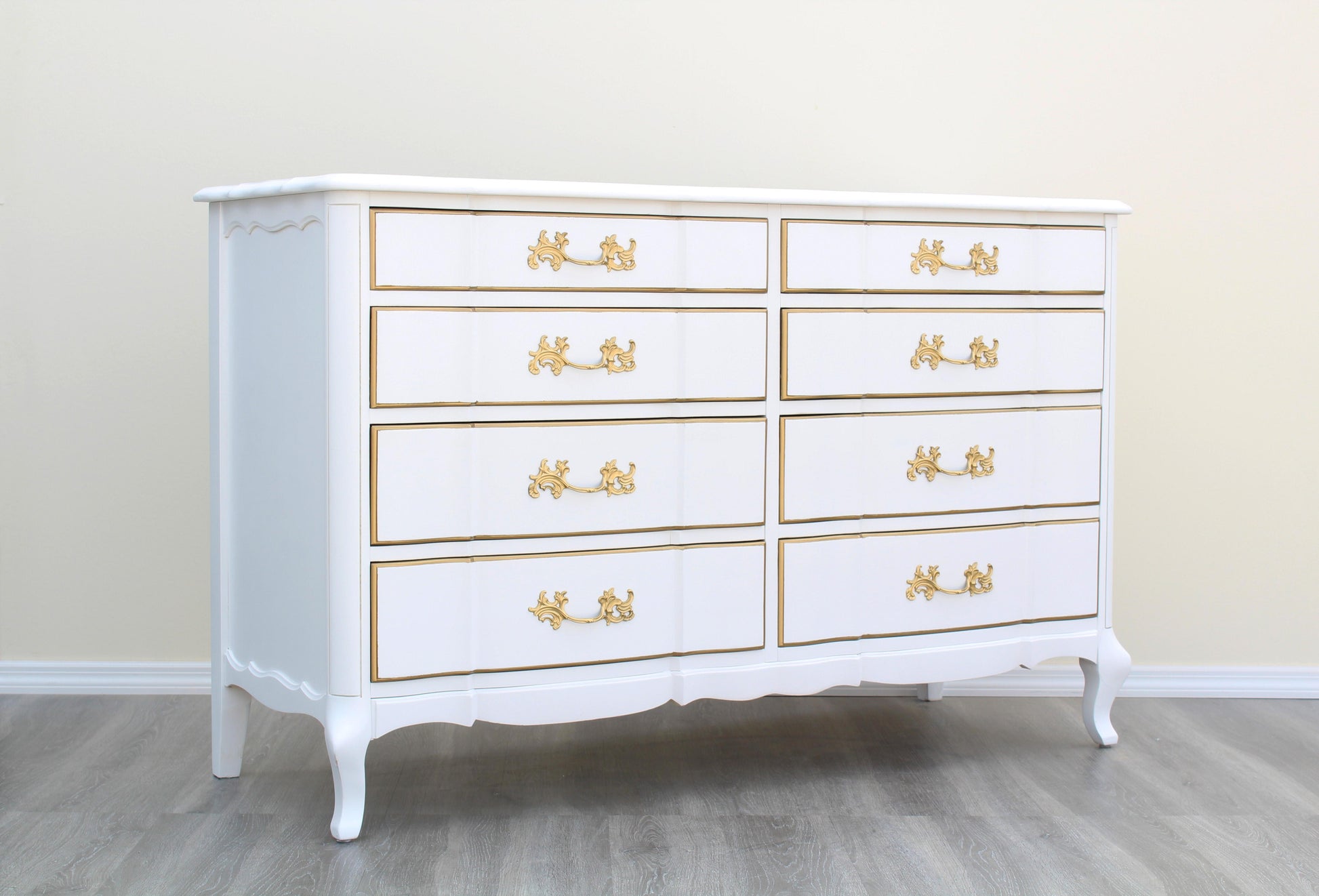 1970's French Provincial Dresser of Eight Drawers by Permacraft.  This dresser is solid built with dovetail joints and metal hardware, is newly refinished in white and gold with a satin topcoat.  Dimensions: 54"Width x 20"Depth x 34"Height. 