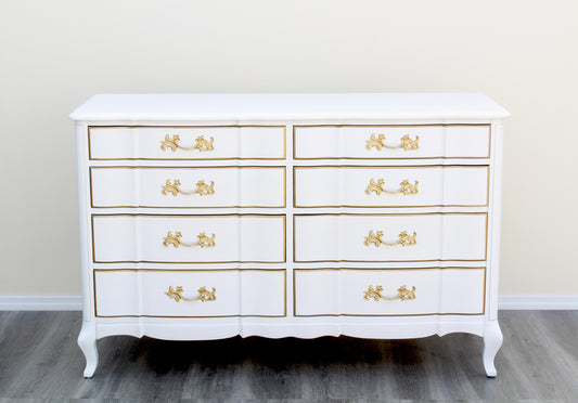 1970's French Provincial Dresser of Eight Drawers by Permacraft.  This dresser is solid built with dovetail joints and metal hardware, is newly refinished in white and gold with a satin topcoat.  Dimensions: 54"Width x 20"Depth x 34"Height. 