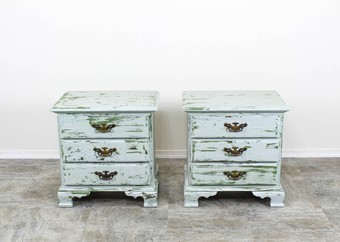 Pair of Mid Century Georgian style nightstands.  This pair of nightstands are hand- painted in green and gray in a  distressed finish  with metal hardware.  Dimensions; 24"Width x 17"Depth x 25"Height. 