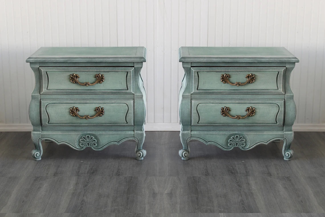 Pair of vintage Bombay nightstands.  These nightstands are professionally refinished in green with dry-brushed finish.  Dimensions, 28"Width x 17"Depth x 26"Height.