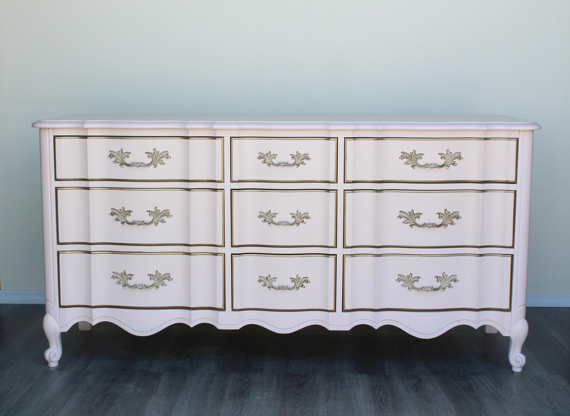 Vintage French provincial solid built dresser of nine drawers.  This dresser was professionally refinished in a Champagne pink and gold with satin top coat.  Dimensions: 64"Width x 20"Depth x 32"Height. 