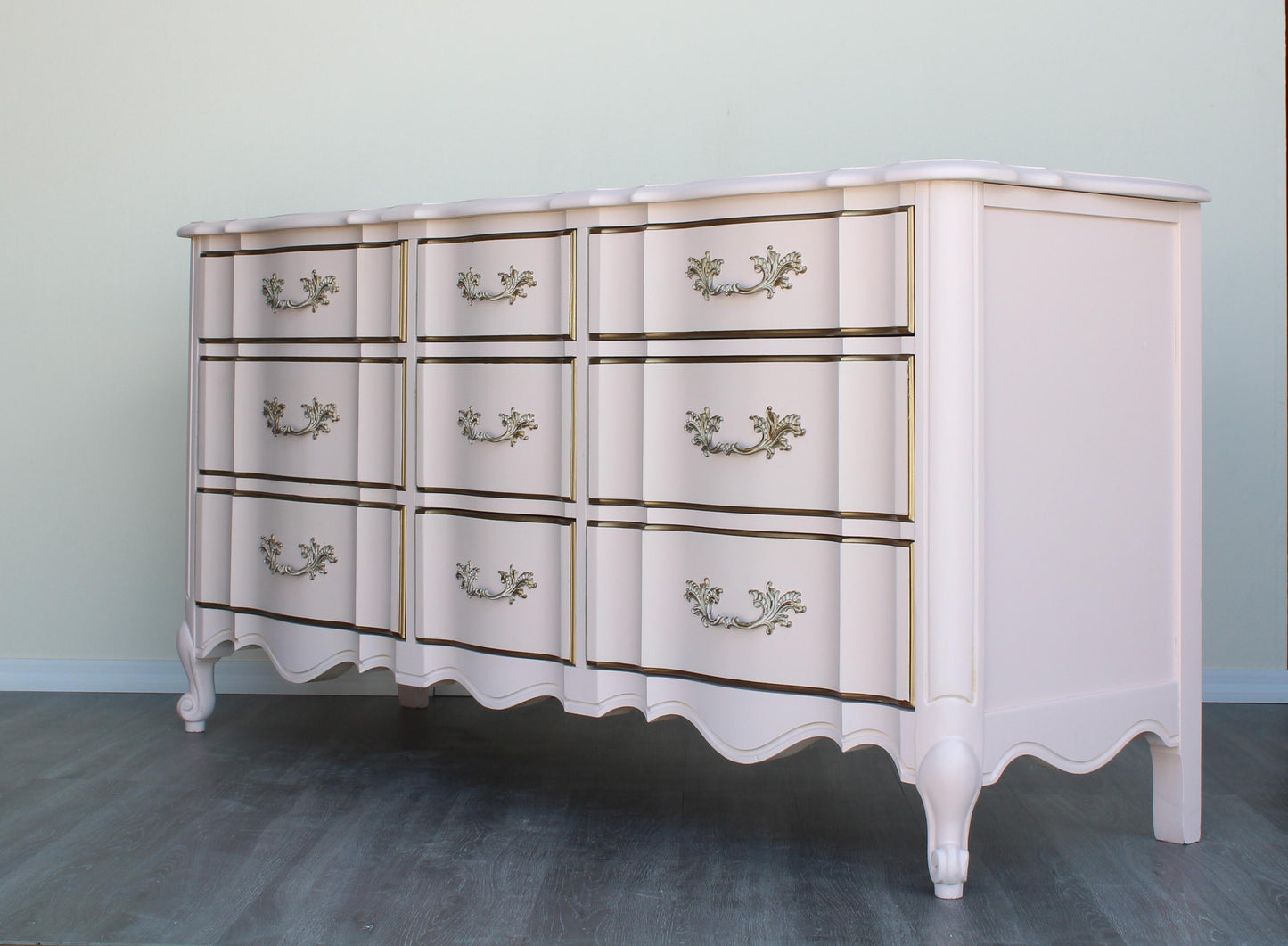 Vintage French provincial solid built dresser of nine drawers.  This dresser was professionally refinished in a Champagne pink and gold with satin top coat.  Dimensions: 64"Width x 20"Depth x 32"Height. 