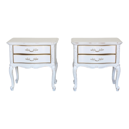 Vintage pair of French provincial nightstands of two drawers.  The nightstands are solid built with dovetail joints, are professionally refinished in white with a distressed finish and gold painted accents.  Dimensions: 24.5"Width x 16"Depth x 24"Height.