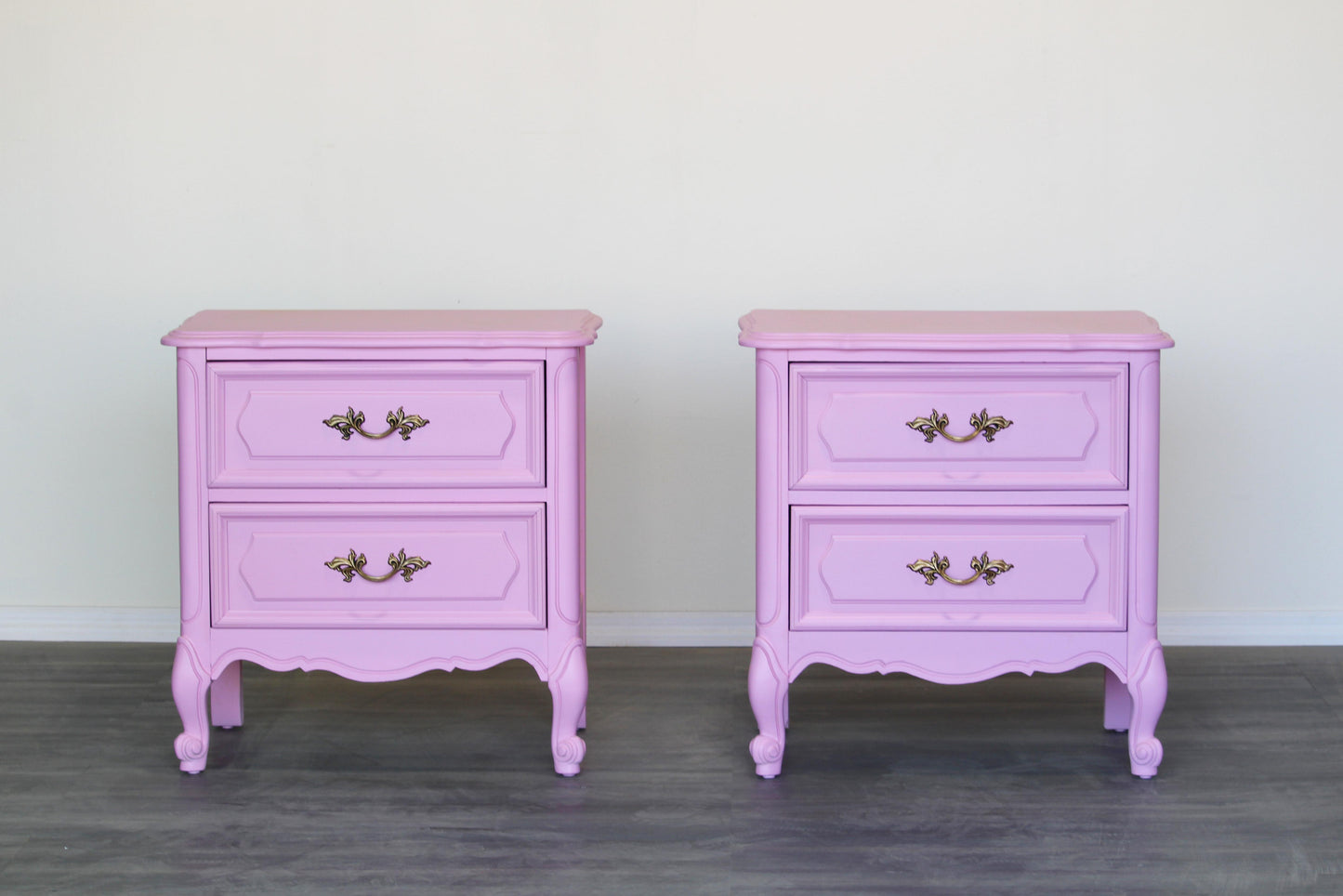 Pair of solid built French style nightstands of two drawers.  The nightstands are professionally refinished in a cotton candy pink with a satin finish.  Dimensions; 24" Width x 16" Depth x 25" Height. 