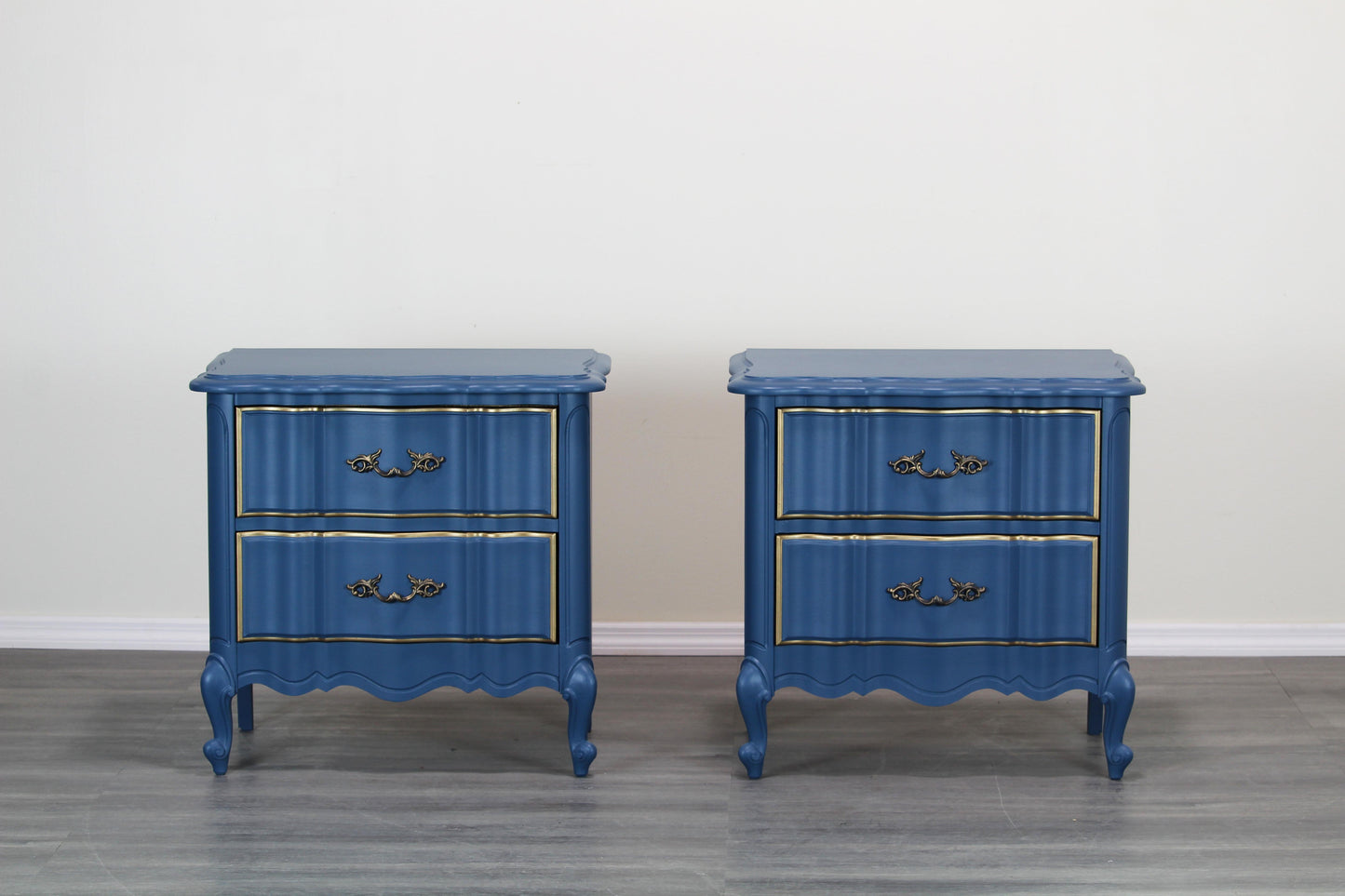 Pair of French provincial blue nightstands of two drawers.  The nightstands are professionally refinished in blue with gold painted accents in a satin finish.  Dimensions; 24" Width x 17"Depth x 24"Height. 