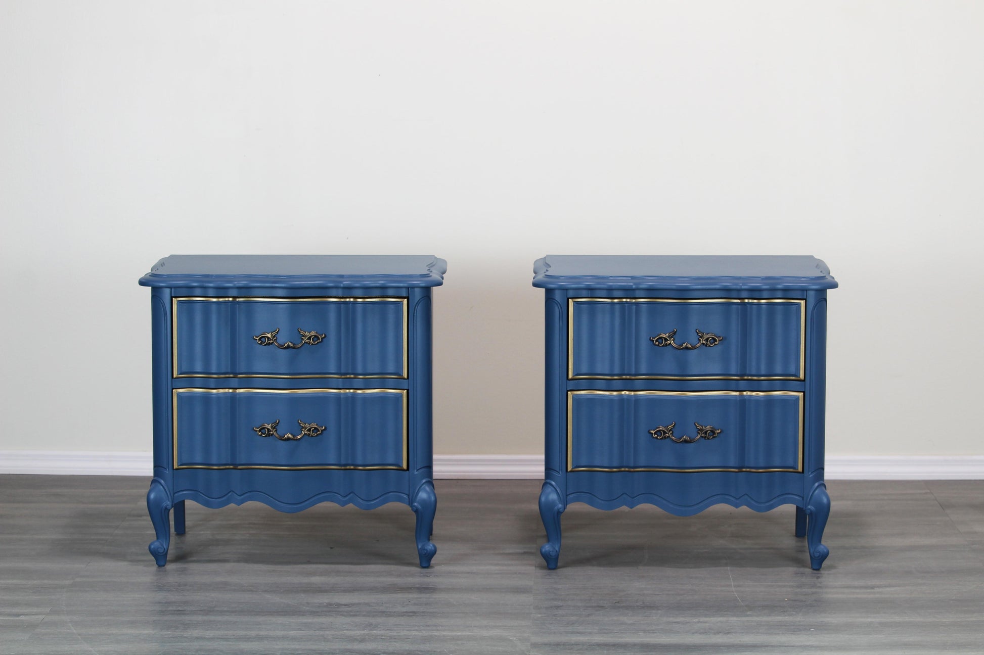 Pair of French provincial blue nightstands of two drawers.  The nightstands are professionally refinished in blue with gold painted accents in a satin finish.  Dimensions; 24" Width x 17"Depth x 24"Height. 