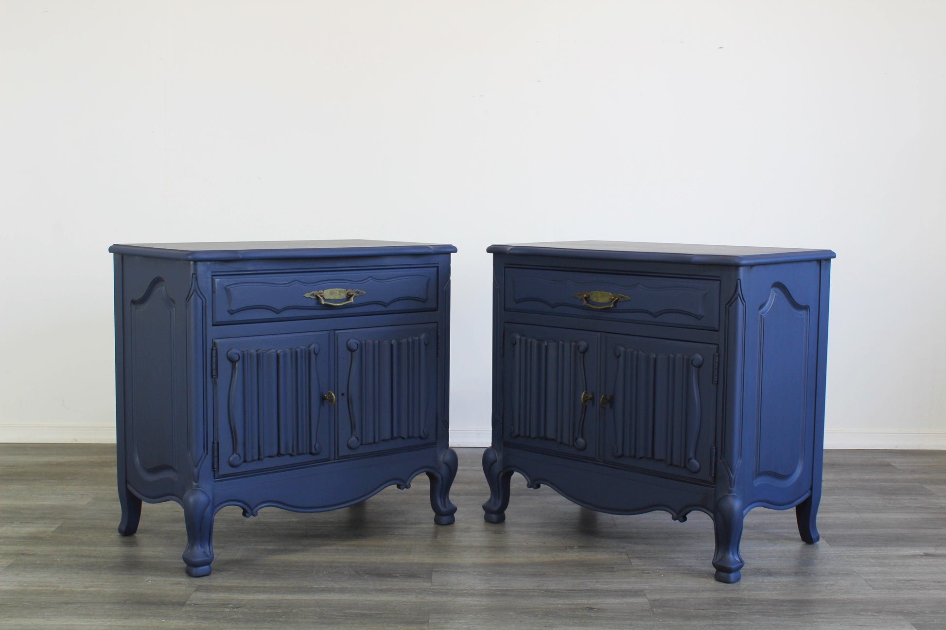 Vintage pair of French Style Nightstands.  These nightstands are solid built with a dovetail drawer and double doors that open to a storage space.  These nightstands are professionally refinished in blue with antique glaze and brass hardware.  Dimensions; 27" Width x 17" Depth x 27" Height. 