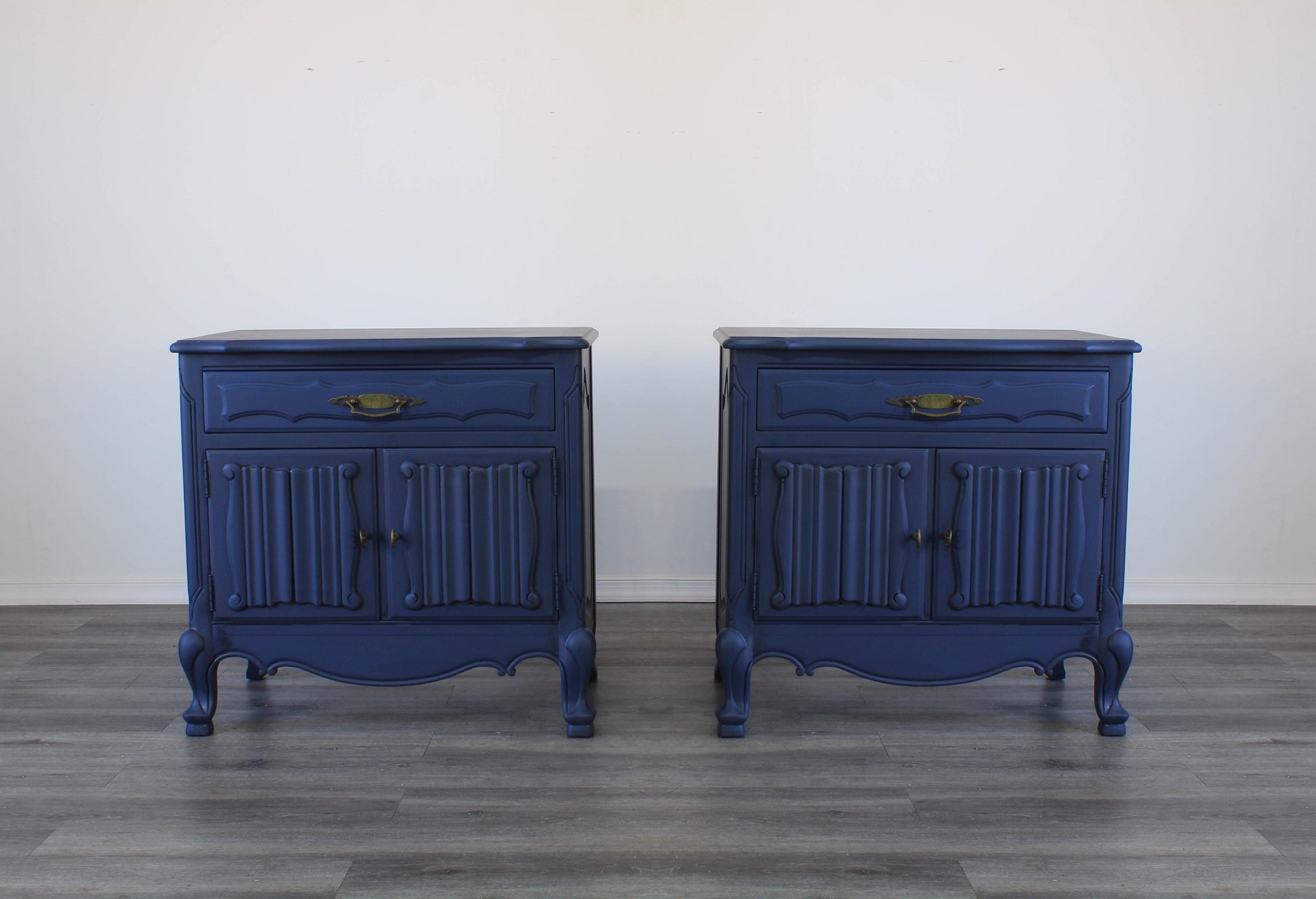 Vintage pair of French Style Nightstands.  These nightstands are solid built with a dovetail drawer and double doors that open to a storage space.  These nightstands are professionally refinished in blue with antique glaze and brass hardware.  Dimensions; 27" Width x 17" Depth x 27" Height. 