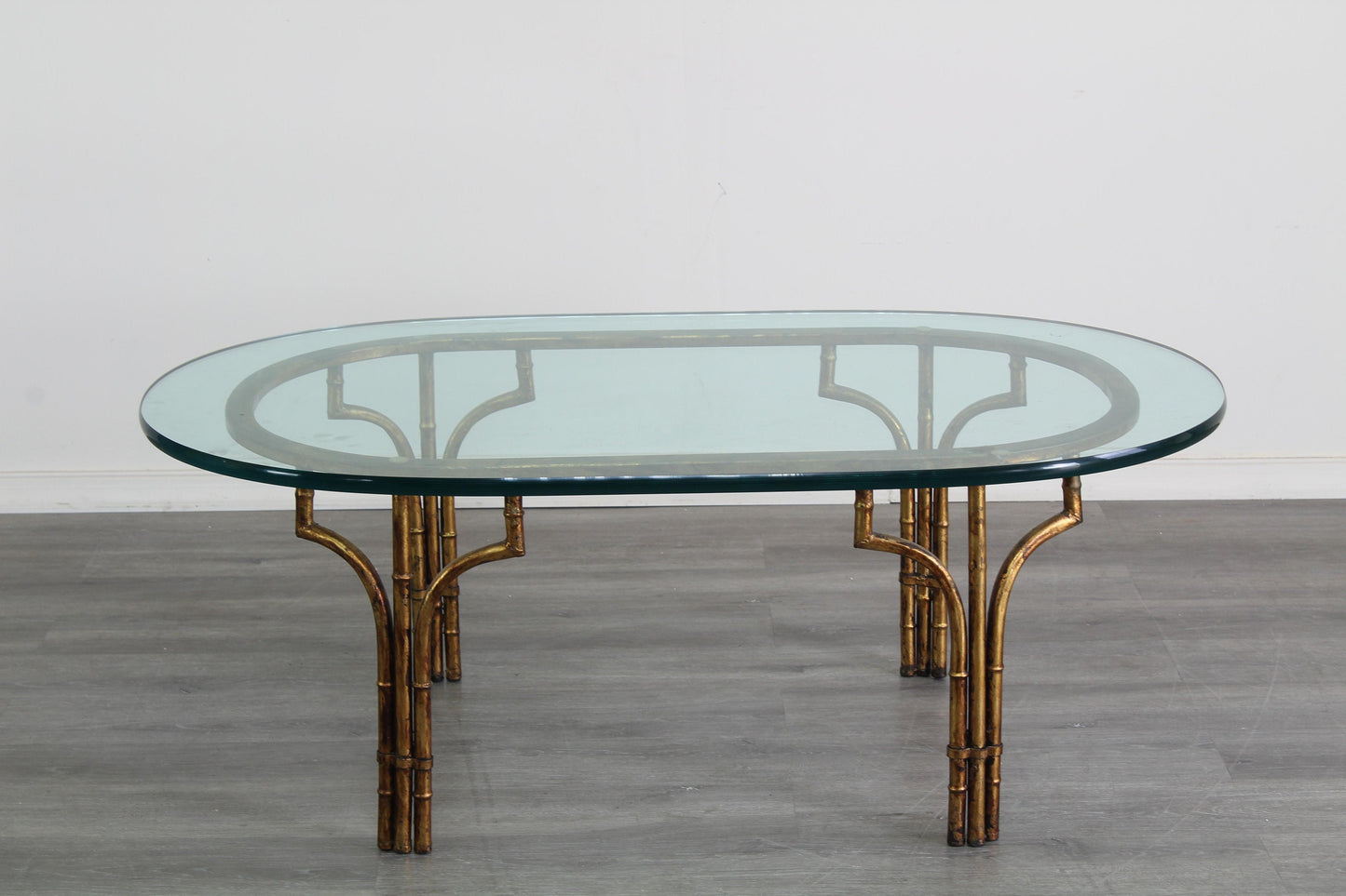 Vintage Hollywood Regency faux bamboo metal coffee table with glass top.  This is a gilt metal oval coffee table with glass top.  Dimensions; 46" Width x 26" Depth x 17" Height. 